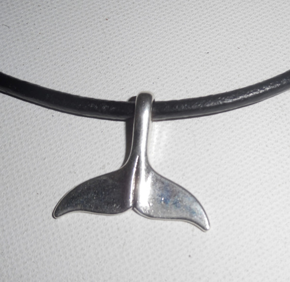 Lucky dolphin tail hängande i silvermetall på svart läder