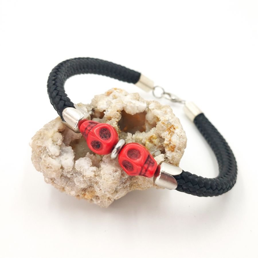 Armband med dubbla dödskallar och korsben med röda stenar på ett tjockt svart rep.